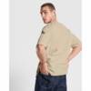 Camiseta Gruesa Oversize Roly 6561 Arena Hombre Hombre luciendo camiseta gruesa oversize Roly 6561 de algodón color arena, con corte holgado, mirando hacia atrás. Perfecta para ropa laboral e industria.
